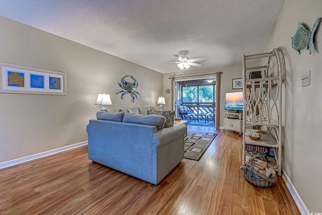 living room featuring ceiling fan, hardwood / wood-style flooring, and a textured ceiling