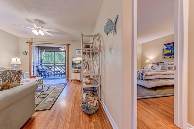 living room featuring ceiling fan, hardwood / wood-style flooring, and a textured ceiling