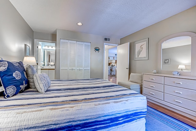 bedroom featuring a closet, ensuite bathroom, and a textured ceiling