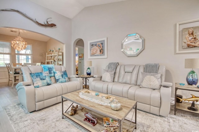 living room featuring a notable chandelier, light wood-type flooring, and vaulted ceiling