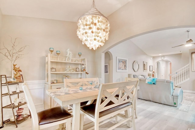 dining room with light hardwood / wood-style flooring, ceiling fan with notable chandelier, and vaulted ceiling