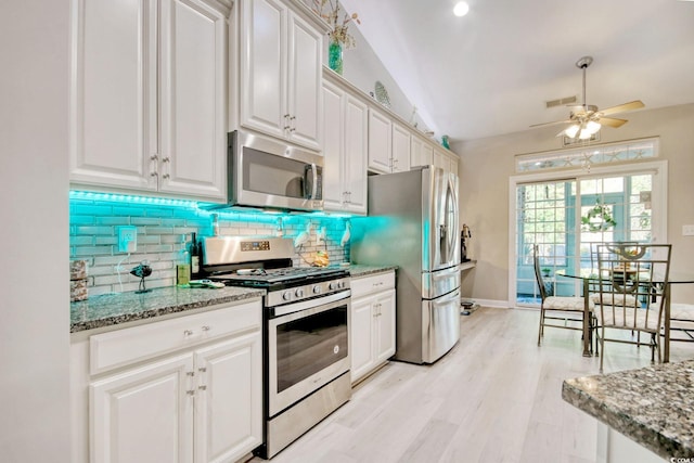 kitchen with white cabinetry, stainless steel appliances, light stone counters, backsplash, and lofted ceiling