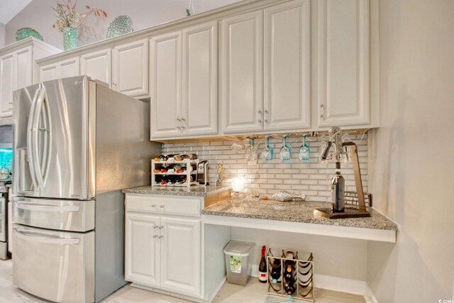 kitchen with white cabinetry, light stone counters, stainless steel fridge with ice dispenser, and tasteful backsplash