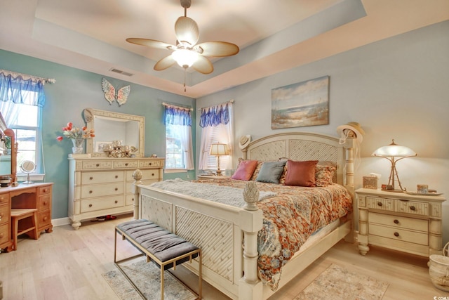 bedroom featuring a raised ceiling, ceiling fan, and light hardwood / wood-style floors