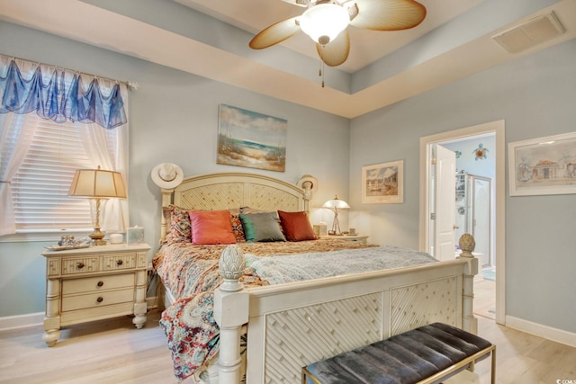 bedroom featuring light wood-type flooring, a raised ceiling, and ceiling fan