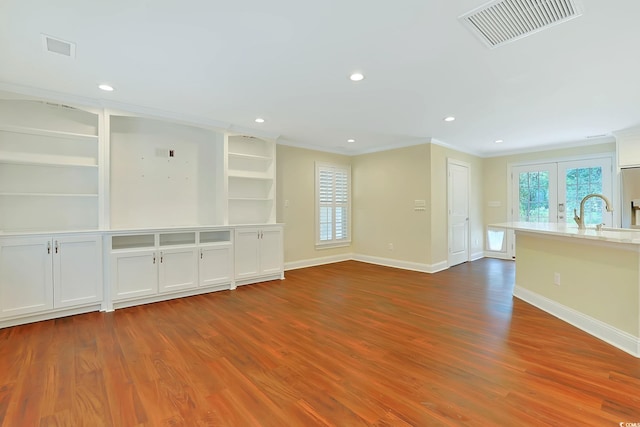 unfurnished living room with ornamental molding, french doors, hardwood / wood-style flooring, and sink