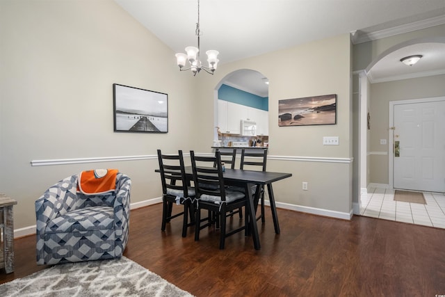 dining area with crown molding, a notable chandelier, lofted ceiling, and dark hardwood / wood-style flooring