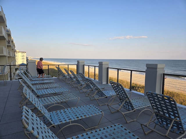 view of patio featuring a water view, a view of the beach, and a balcony