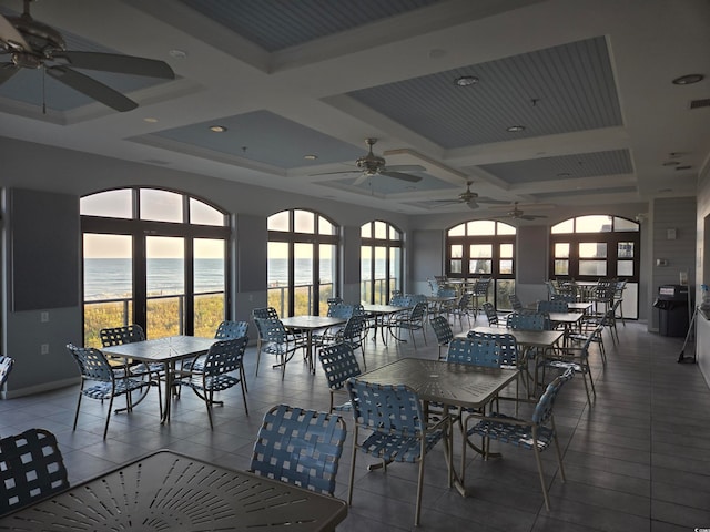 tiled dining space featuring a water view, ceiling fan, coffered ceiling, and beamed ceiling