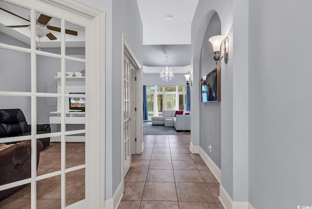 corridor featuring french doors, tile patterned flooring, and a notable chandelier