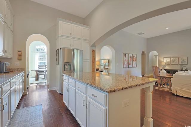 kitchen featuring white cabinetry, light stone counters, dark hardwood / wood-style floors, and a center island