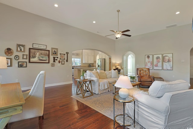 living room featuring a high ceiling, ceiling fan, and dark hardwood / wood-style floors