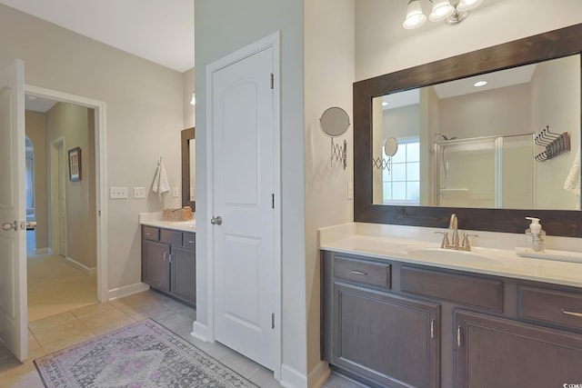 bathroom with walk in shower, vanity, and tile patterned floors