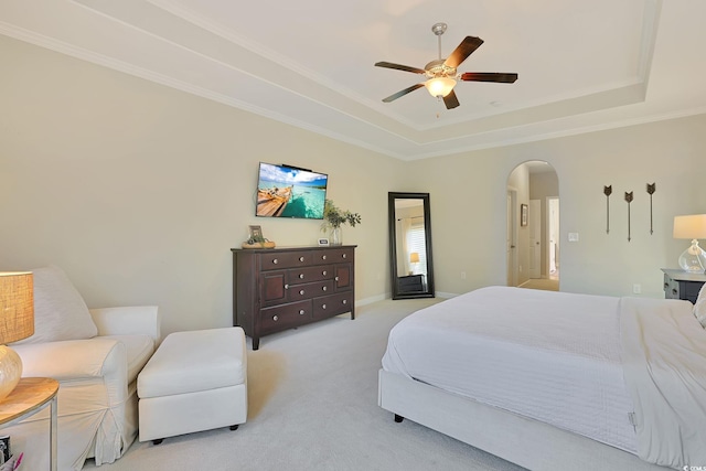 bedroom featuring ornamental molding, light colored carpet, ceiling fan, and a tray ceiling