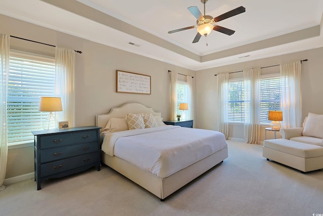 carpeted bedroom featuring ornamental molding, a raised ceiling, multiple windows, and ceiling fan