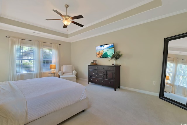 carpeted bedroom with ceiling fan, a tray ceiling, and ornamental molding