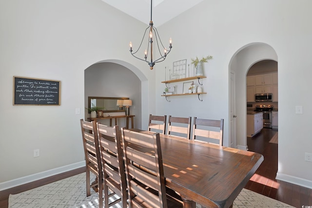 dining area featuring dark wood-type flooring, high vaulted ceiling, and a notable chandelier