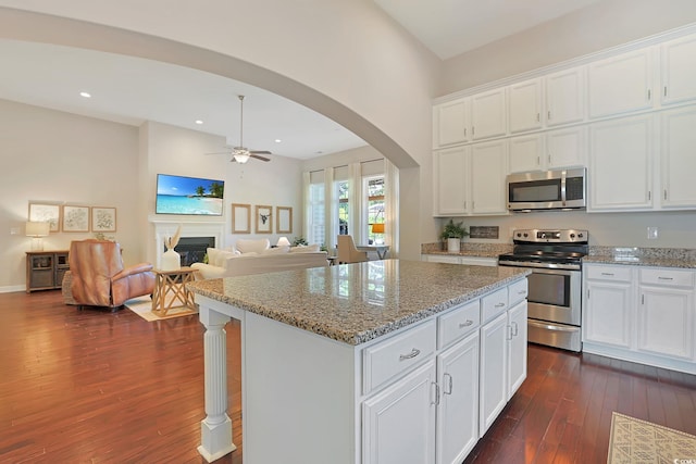 kitchen with dark hardwood / wood-style flooring, a kitchen island, white cabinetry, and appliances with stainless steel finishes