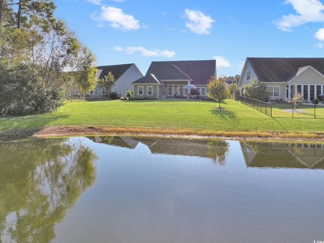 back of property with a water view and a yard