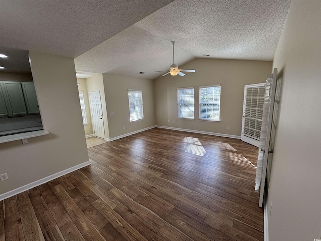 unfurnished living room featuring vaulted ceiling, dark wood-type flooring, a textured ceiling, and ceiling fan