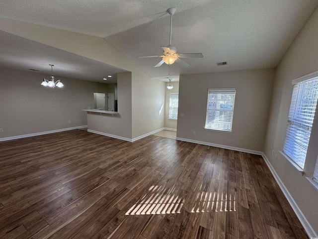 unfurnished living room featuring vaulted ceiling, dark hardwood / wood-style flooring, a textured ceiling, and ceiling fan with notable chandelier