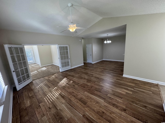 unfurnished living room featuring ceiling fan with notable chandelier, dark wood-type flooring, and lofted ceiling