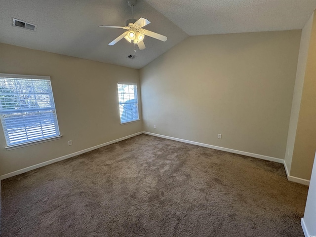 unfurnished room featuring ceiling fan, vaulted ceiling, dark carpet, and a textured ceiling