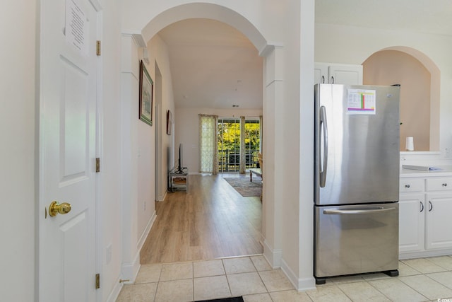 kitchen featuring light hardwood / wood-style floors, stainless steel refrigerator, and white cabinets