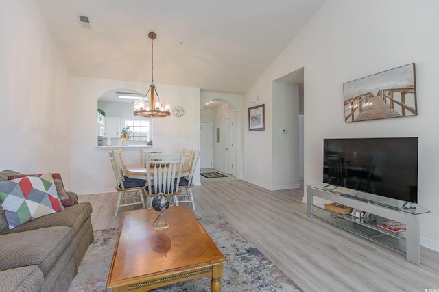 living room featuring vaulted ceiling, a notable chandelier, and light hardwood / wood-style flooring