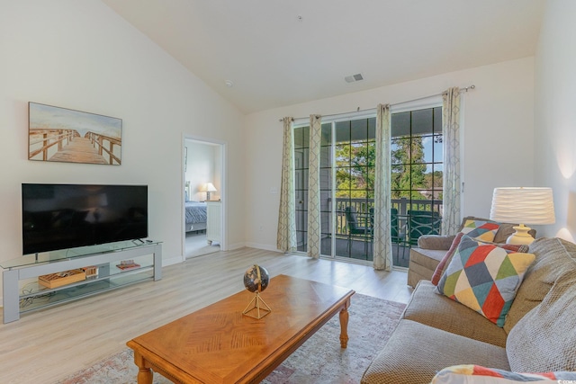 living room with high vaulted ceiling and light wood-type flooring