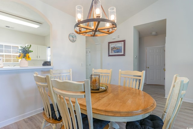 dining room with light hardwood / wood-style floors, a notable chandelier, and lofted ceiling