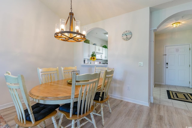 dining room with vaulted ceiling, light hardwood / wood-style flooring, and a notable chandelier