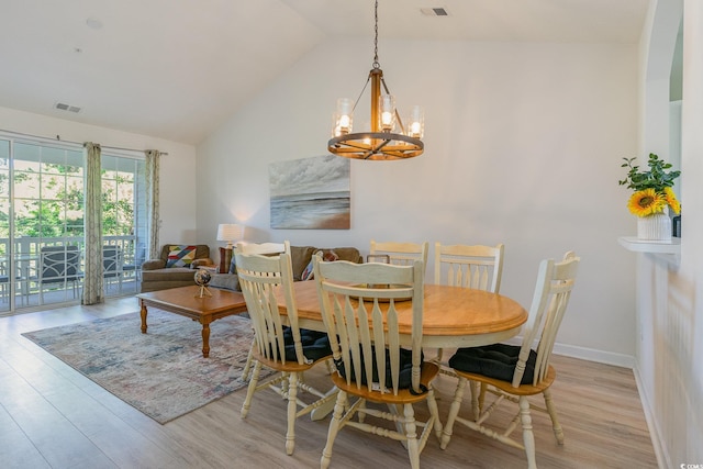 dining room featuring high vaulted ceiling, light hardwood / wood-style flooring, and an inviting chandelier