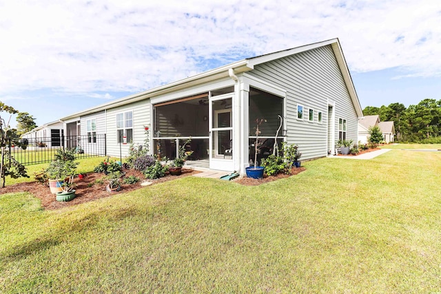 rear view of house with a sunroom and a lawn