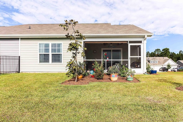 rear view of property featuring a sunroom and a lawn