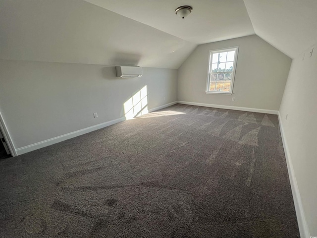 additional living space featuring a wall mounted air conditioner, lofted ceiling, and dark colored carpet