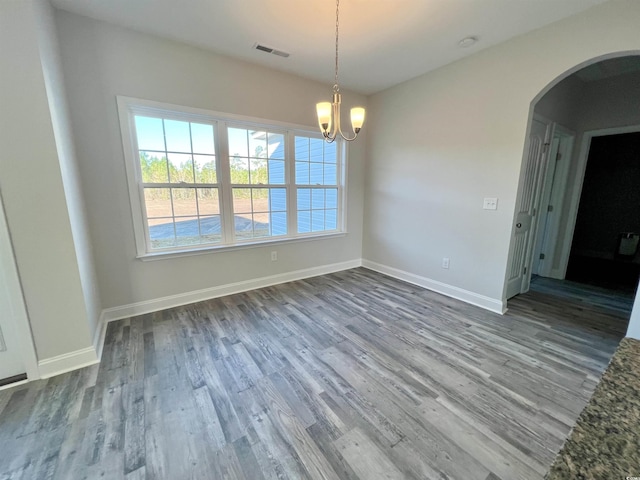 unfurnished dining area featuring wood-type flooring and an inviting chandelier