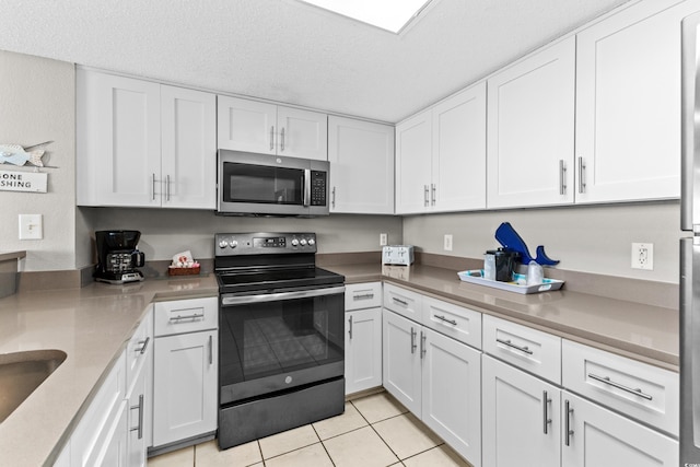 kitchen with white cabinetry, light tile patterned floors, stainless steel appliances, and a textured ceiling