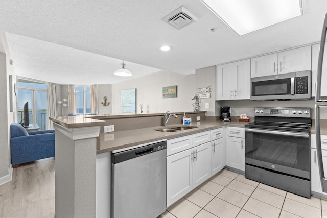 2701 S Ocean Blvd Unit 1817, North Myrtle Beach, SC 29582 - kitchen featuring appliances with stainless steel finishes, a peninsula, white cabinetry, open floor plan, and a textured ceiling
