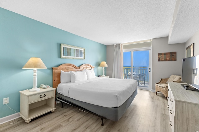 bedroom featuring access to outside, a textured ceiling, and light wood-type flooring