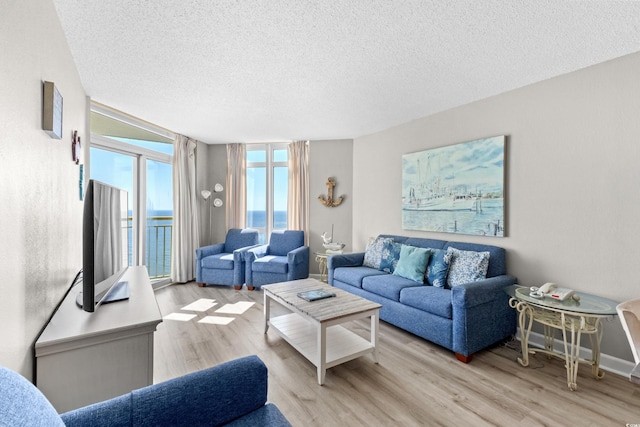 living room with a wall of windows, a textured ceiling, and light hardwood / wood-style flooring