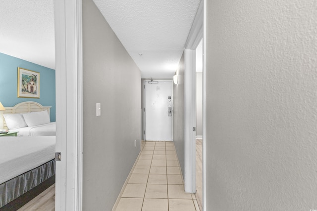 hallway with light tile patterned flooring and a textured ceiling