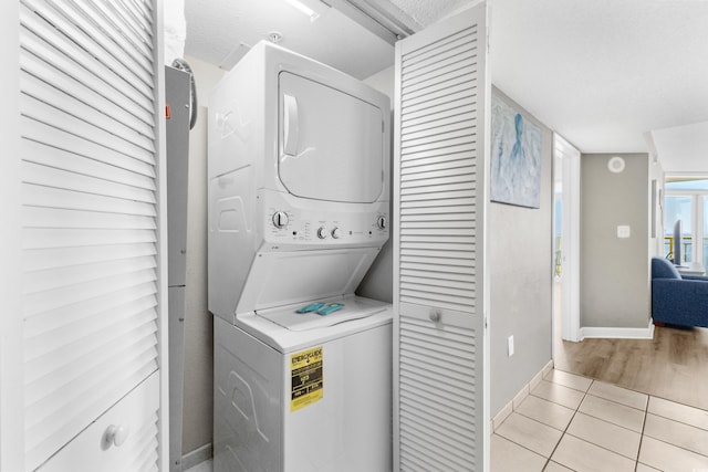 washroom featuring light tile patterned floors, a textured ceiling, and stacked washer / dryer