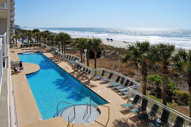 view of pool featuring a patio area, a view of the beach, and a water view