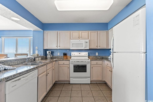 kitchen with a sink, light tile patterned floors, and white appliances
