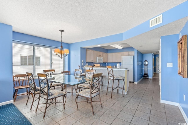 dining space with a notable chandelier, a textured ceiling, and light tile patterned floors