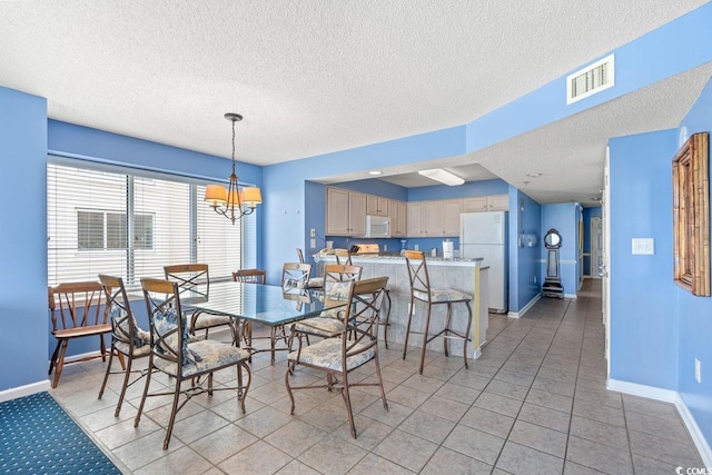 dining area featuring baseboards, a chandelier, a textured ceiling, and visible vents