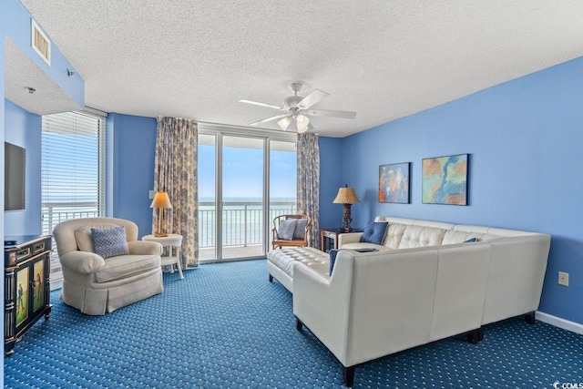 living area with carpet floors, ceiling fan, a water view, and a healthy amount of sunlight