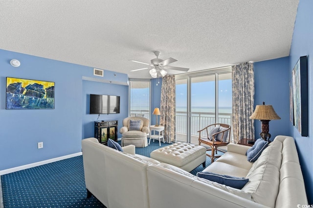 carpeted living room with a wall of windows, a ceiling fan, a textured ceiling, visible vents, and baseboards