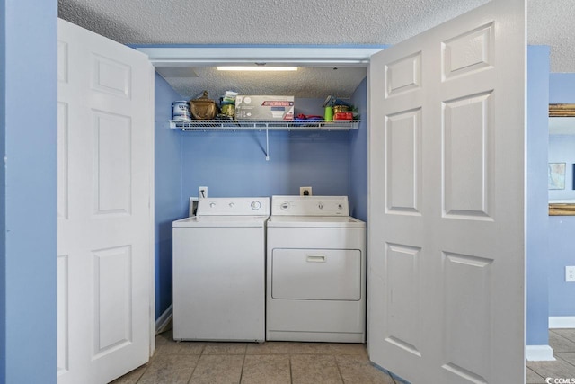 laundry area featuring separate washer and dryer, laundry area, a textured ceiling, and light tile patterned floors